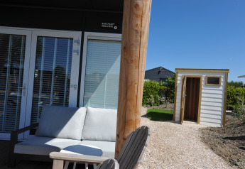 Area esterna con divano e casetta presso Beach Loft + Wellness al Camping Zonneweelde nei Paesi Bassi.