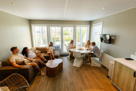 Vijf jongeren ontspannen samen in de lichte en moderne leefruimte van Beach Loft + Wellness in Nederland.
