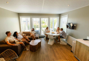 Cinque giovani adulti conversano e si rilassano nel soggiorno luminoso del Beach Loft + Wellness nei Paesi Bassi.