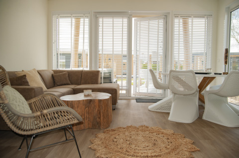 Salón moderno en Beach Loft + Wellness de Camping Zonneweelde, Países Bajos, con amplias ventanas y decoración acogedora.