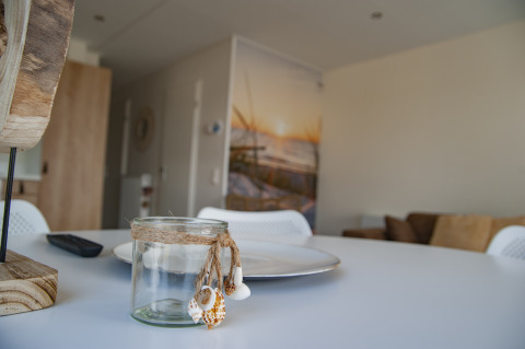 Sfeervol lodge-interieur met versierd glas, bord en afstandsbediening op een witte ronde tafel.