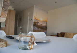 Interior acogedor de lodge con tarro decorativo, plato y mando a distancia sobre una mesa blanca.