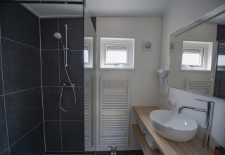 Bagno moderno con doccia nera, lavabo rotondo, piano in legno e termosifone a Camping Zonneweelde, Beach Loft.
