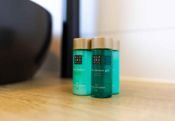 Tres botellas de productos Rituals sobre una superficie de madera en una habitación de lodge luminosa.