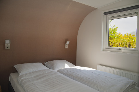 Moderne slaapkamer met twee bedden en veel licht in Beach Loft + Wellness bij Camping Zonneweelde.