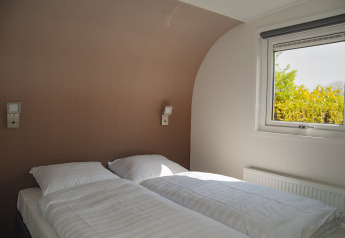 En moderne soveværelseslodge med to senge, vindue og naturligt lys på Camping Zonneweelde i Holland.
