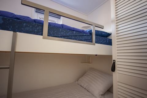 Moderne stapelbedkamer met blauw-wit beddengoed in Beach Loft + Wellness bij Camping Zonneweelde.