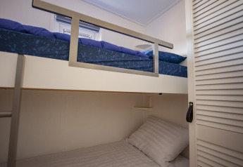Chambre avec lits superposés modernes, draps bleus et blancs au Beach Loft + Wellness du Camping Zonneweelde.