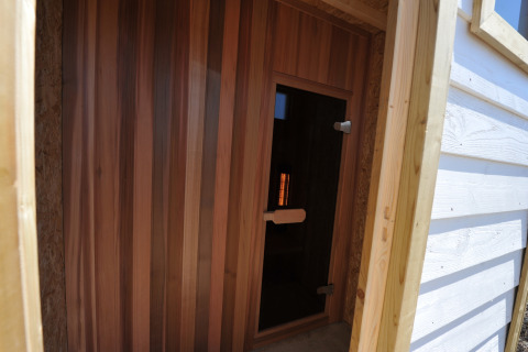 Ingang van een houten sauna bij Beach Loft + Wellness, Camping Zonneweelde in Nederland, van buitenaf gezien.