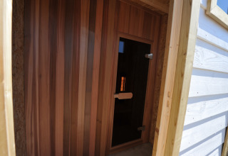 Entrada a una sauna de madera en Beach Loft + Wellness, Camping Zonneweelde, Países Bajos, vista desde fuera.