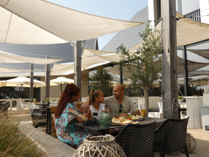 Familie isst gemeinsam draußen bei Beach Loft + Wellness im Camping Zonneweelde, Niederlande.
