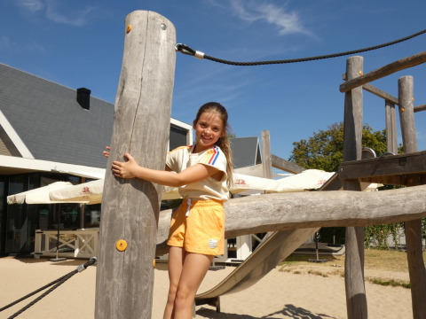 Fille jouant sur une aire de jeux à Beach Loft + Wellness, Camping Zonneweelde, Pays-Bas, journée ensoleillée.