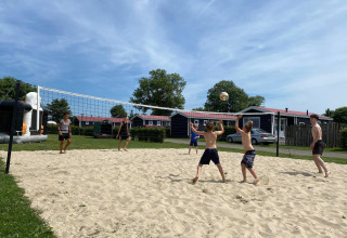 Mensen spelen beachvolleybal bij Beach Loft + Wellness op Camping Zonneweelde in Nederland op een zonnige dag.