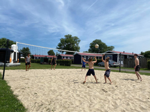 Menschen spielen Beachvolleyball vor Beach Loft + Wellness im Camping Zonneweelde in den Niederlanden.
