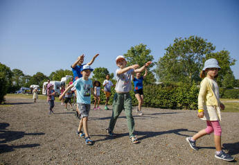 Bambini e adulti giocano all'aperto sotto il sole al Beach Loft + Wellness, Camping Zonneweelde, Paesi Bassi.