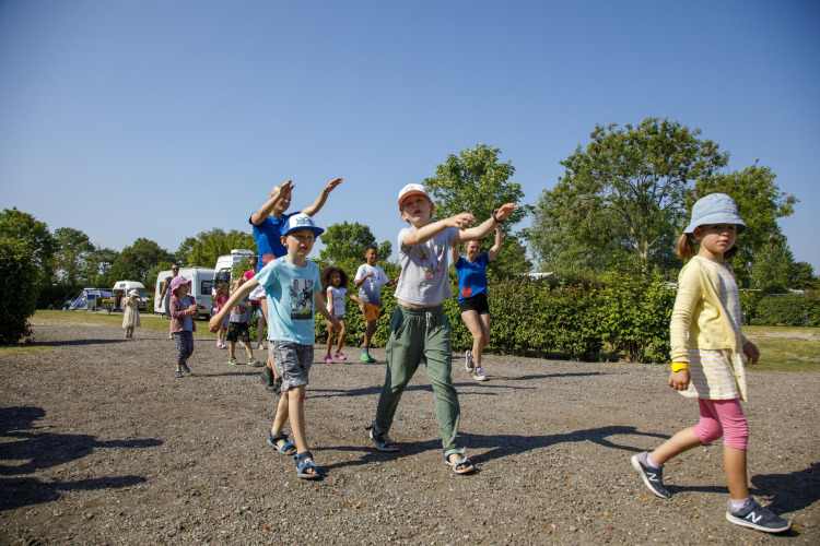 Kinder und Erwachsene spielen draußen bei sonnigem Wetter im Beach Loft + Wellness, Camping Zonneweelde, Niederlande.