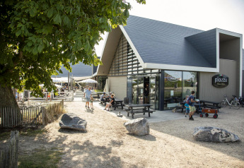 Outdoor view of Beach Loft + Wellness at Camping Zonneweelde in the Netherlands, showing people and building.