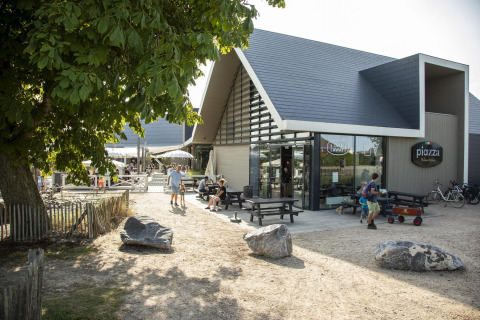 Vue extérieure de Beach Loft + Wellness au Camping Zonneweelde aux Pays-Bas, avec personnes et bâtiment moderne.