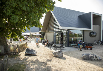 Vista exterior de Beach Loft + Wellness en Camping Zonneweelde, Países Bajos, con personas y edificio moderno.