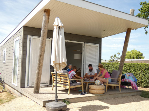 Familia disfruta en la terraza de una Beach Loft en Camping Zonneweelde, Países Bajos, en un ambiente veraniego.