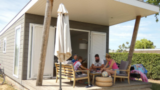 Familia disfruta en la terraza de una Beach Loft en Camping Zonneweelde, Países Bajos, en un ambiente veraniego.
