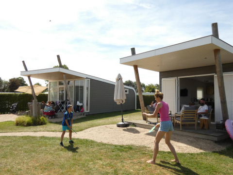Gezin speelt buiten aan Beach Loft op Camping Zonneweelde in Nederland tijdens een zonnige dag.