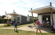 Familie nyder en solrig dag ved Beach Loft på Camping Zonneweelde i Holland med udendørs aktiviteter.
