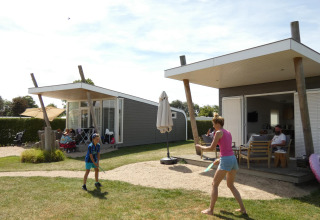 Familie nyder en solrig dag ved Beach Loft på Camping Zonneweelde i Holland med udendørs aktiviteter.