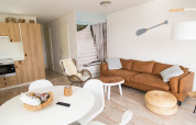 Lichte strandthema woonkamer in Beach Loft op Camping Zonneweelde, Nederland, met moderne inrichting.