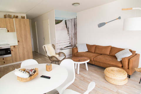 Lyst strandinspireret opholdsområde i Beach Loft på Camping Zonneweelde, Holland, med moderne møbler.