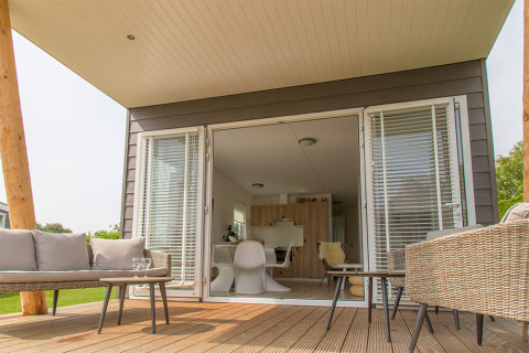 Terrazza esterna al Beach Loft di Camping Zonneweelde, Paesi Bassi, con arredi moderni e porte aperte.