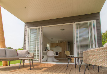 Buitenterras bij Beach Loft op Camping Zonneweelde in Nederland met moderne meubels en openstaande deuren.