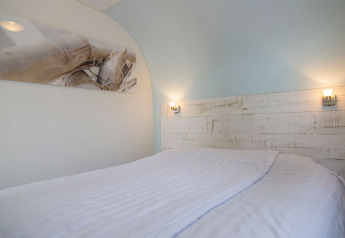 Camera luminosa al Beach Loft di Camping Zonneweelde, Paesi Bassi, con biancheria bianca e decorazione.