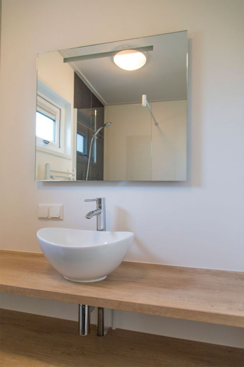 Moderno lavabo de baño con espejo y encimera de madera en Beach Loft de Camping Zonneweelde, Países Bajos.