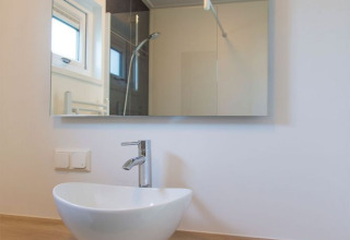 Moderne badeværelseshåndvask med spejl og træbordplade i Beach Loft på Camping Zonneweelde, Holland.