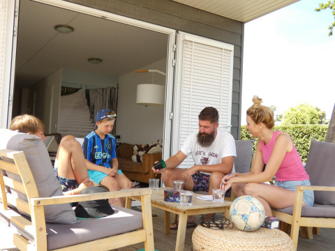 Gezin ontspant op het terras van Beach Loft aan Camping Zonneweelde in Nederland.