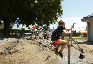 Bambini che giocano con acqua e sabbia al Beach Loft di Camping Zonneweelde nei Paesi Bassi.