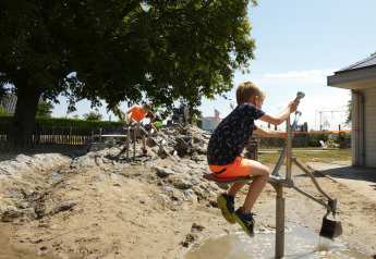 Des enfants jouent avec des équipements d’eau et de sable au Beach Loft, Camping Zonneweelde aux Pays-Bas.