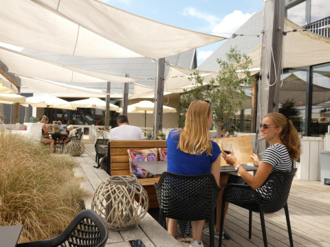 Deux femmes assises en terrasse au Beach Loft du Camping Zonneweelde, Pays-Bas, profitant d'une journée ensoleillée.