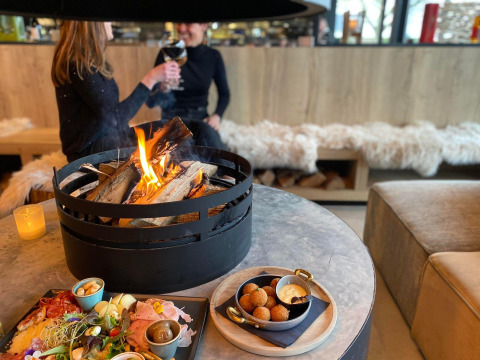 Due persone gustano cibo e bevande vicino a un fuoco al Beach Loft presso Camping Zonneweelde, Paesi Bassi.