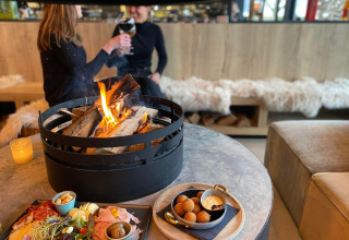 Due persone gustano cibo e bevande vicino a un fuoco al Beach Loft presso Camping Zonneweelde, Paesi Bassi.