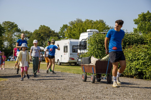 Bambini e adulti camminano e tirano un carretto al Beach Loft di Camping Zonneweelde, Olanda, giornata di sole.