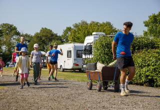 Bambini e adulti camminano e tirano un carretto al Beach Loft di Camping Zonneweelde, Olanda, giornata di sole.