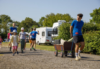 Bambini e adulti camminano e tirano un carretto al Beach Loft di Camping Zonneweelde, Olanda, giornata di sole.