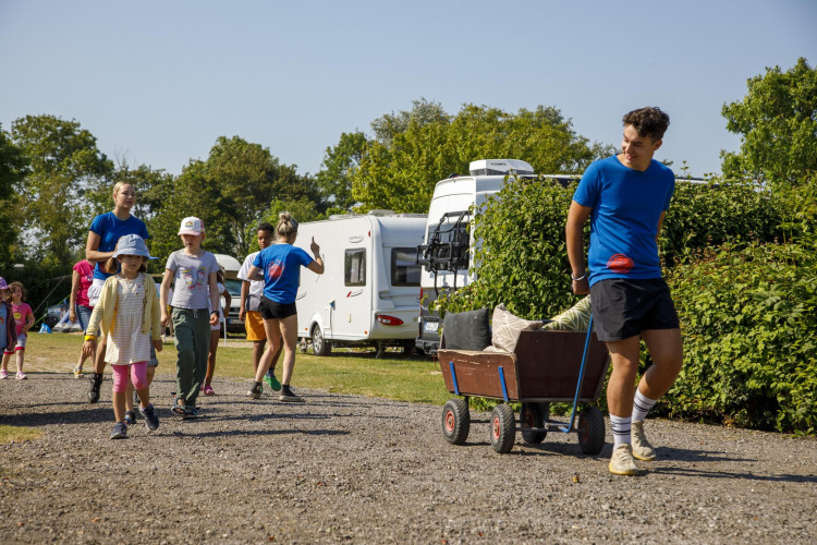 Children and adults walking and pulling a cart at Beach Loft, Camping Zonneweelde, Netherlands, sunny day.