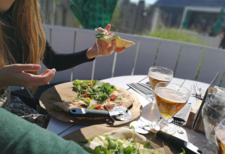 Comida al aire libre en Beach Loft en Camping Zonneweelde, Países Bajos, con pizza y cerveza.