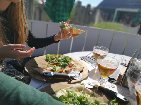 Repas en plein air au Beach Loft de Camping Zonneweelde, Pays-Bas, avec pizza, salade et bière.
