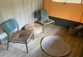 Acogedor rincón en Glampingtent Family - Gent en Bélgica con sillas, alfombras y cestos de mimbre.