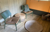 Accogliente angolo relax in una tenda glamping in Belgio con sedie in vimini, tappeti e ceste.
