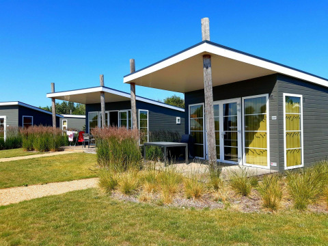 Pequeñas casas modernas en Comfort Lodge, Kompas Camping Nieuwpoort, Bélgica, con césped y cielo azul.